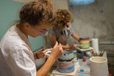 Due partecipanti dipingono il loro vaso in terracotta.