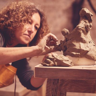 Monica modella una scultura con l'argilla.